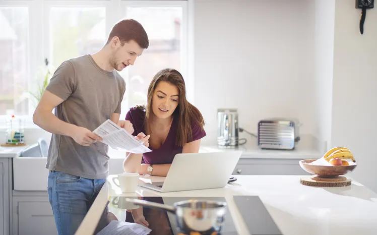 Couple looking at computer together in kitchen